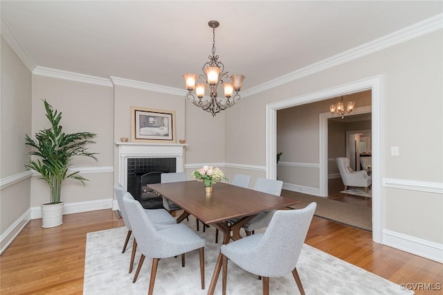 2923 Monument Ave Unit 1, Richmond, VA 23221 - dining area featuring a chandelier, light wood-style floors, a fireplace, crown molding, and baseboards
