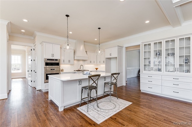 1555 Smokey Ridge Rd, Maidens, VA 23102 - kitchen with custom range hood, white cabinetry, double oven, a kitchen island with sink, and ornamental molding