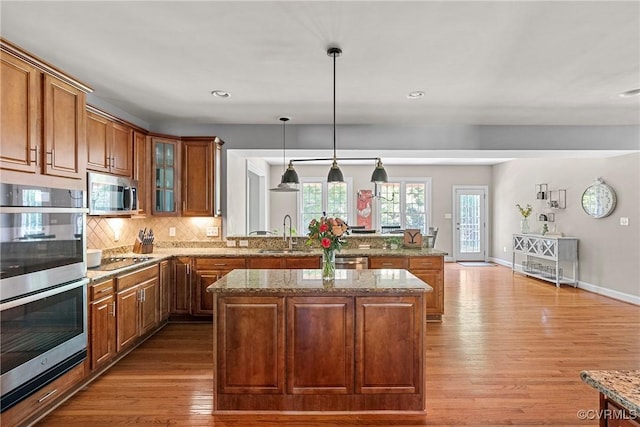 14136 Rigney Dr, Midlothian, VA 23113 - kitchen featuring a sink, stainless steel appliances, wood finished floors, brown cabinets, and a peninsula