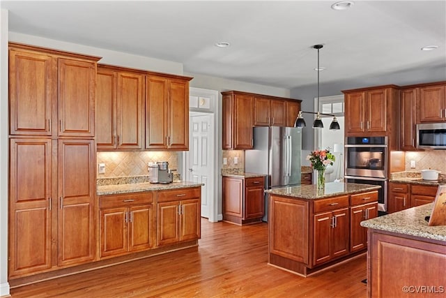 14136 Rigney Dr, Midlothian, VA 23113 - kitchen featuring stainless steel appliances, backsplash, brown cabinetry, light stone counters, and recessed lighting