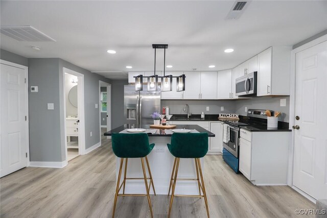 935 Wilcox St, Petersburg, VA 23803 - kitchen featuring appliances with stainless steel finishes, a sink, dark countertops, white cabinets, and light wood finished floors