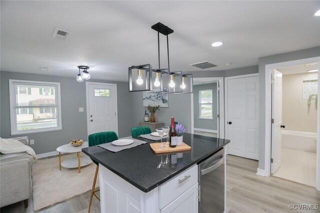 935 Wilcox St, Petersburg, VA 23803 - kitchen with white cabinetry, light wood-type flooring, baseboards, a breakfast bar, and dishwasher