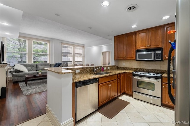 6 N 6th St Unit U2B, Richmond, VA 23219 - kitchen with stainless steel appliances, a sink, a peninsula, light stone countertops, and brown cabinetry