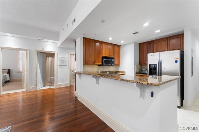 6 N 6th St Unit U2B, Richmond, VA 23219 - kitchen featuring appliances with stainless steel finishes, dark stone counters, a peninsula, baseboards, and recessed lighting