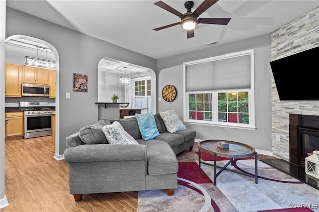 1753 Rose Mill Cir, Midlothian, VA 23112 - living room with light wood finished floors, arched walkways, a ceiling fan, a chandelier, and a stone fireplace