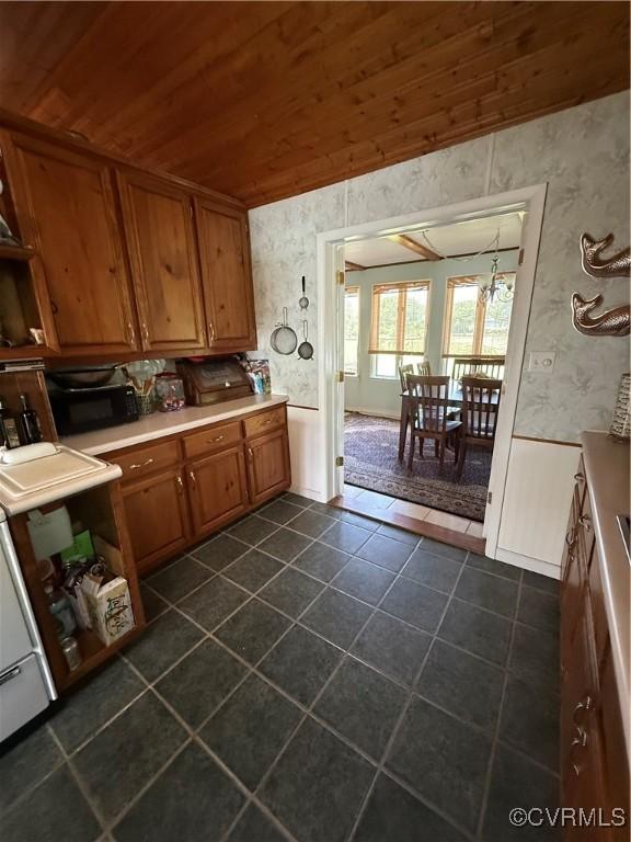 1686 Locust Grove Rd, Topping, VA 23169 - kitchen featuring wallpapered walls, brown cabinets, wood ceiling, dark tile patterned floors, and black microwave
