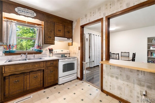 19504 Walker Ave, Chesterfield, VA 23834 - kitchen with white range with electric stovetop, under cabinet range hood, a sink, light countertops, and wallpapered walls