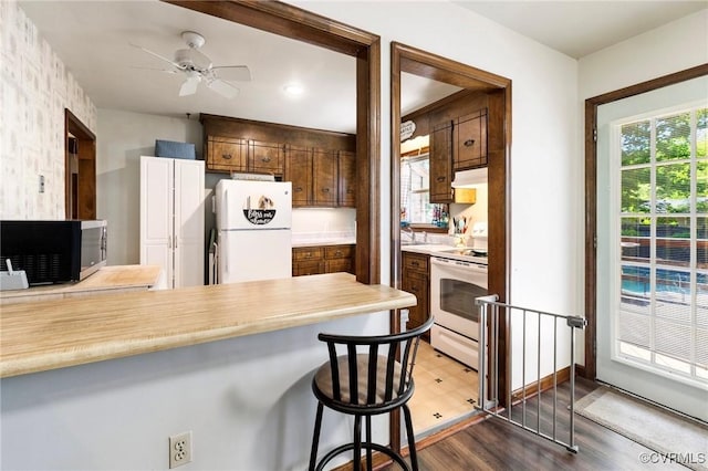 19504 Walker Ave, Chesterfield, VA 23834 - kitchen with white appliances, light countertops, a ceiling fan, under cabinet range hood, and a peninsula