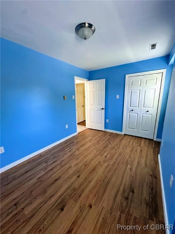 402 N Ivy Ave, Highland Springs, VA 23075 - unfurnished bedroom featuring wood finished floors, baseboards, and a closet