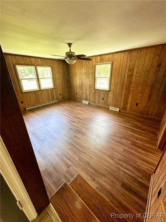 402 N Ivy Ave, Highland Springs, VA 23075 - unfurnished room featuring a baseboard heating unit, wood finished floors, wood walls, and ceiling fan