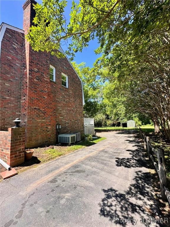 402 N Ivy Ave, Highland Springs, VA 23075 - view of side of property featuring cooling unit, a chimney, brick siding, and asphalt driveway