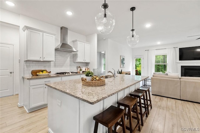 15637 Cedarville Dr, Midlothian, VA 23112 - kitchen featuring wall chimney exhaust hood, stainless steel gas stovetop, light wood finished floors, open floor plan, and a sink