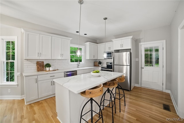 11320 Glendevon Rd, Chesterfield, VA 23838 - kitchen with appliances with stainless steel finishes, light wood finished floors, a kitchen breakfast bar, decorative backsplash, and white cabinets