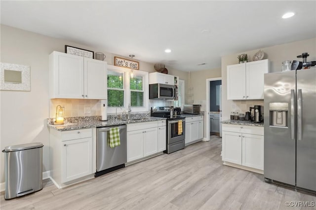 6286 Mcclellan Rd, Mechanicsville, VA 23111 - kitchen with appliances with stainless steel finishes, tasteful backsplash, white cabinetry, light stone counters, and light wood-style floors
