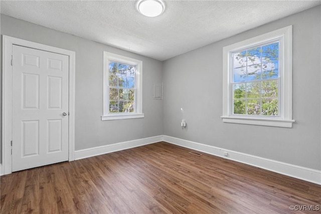 512 St Andrew St, Petersburg, VA 23803 - unfurnished bedroom featuring wood finished floors, multiple windows, baseboards, and a textured ceiling