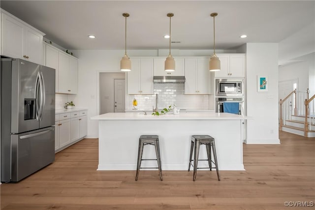 7025 Leire Dr, Chester, VA 23832 - kitchen with stainless steel appliances, under cabinet range hood, a sink, tasteful backsplash, and white cabinetry