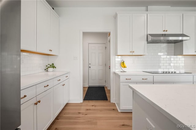 7025 Leire Dr, Chester, VA 23832 - kitchen featuring under cabinet range hood, black electric stovetop, light wood-style floors, white cabinets, and decorative backsplash
