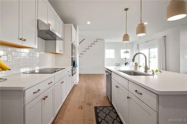 7025 Leire Dr, Chester, VA 23832 - kitchen featuring under cabinet range hood, stainless steel appliances, a sink, decorative backsplash, and light wood-style floors