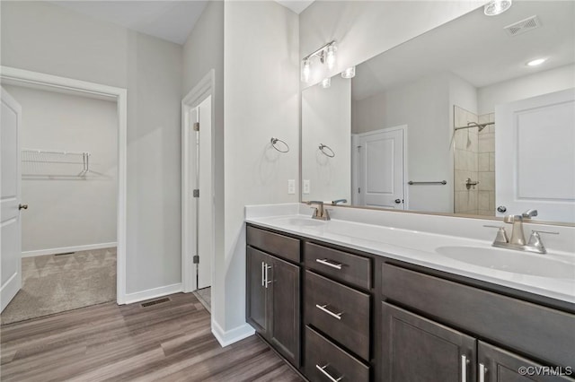 1343 Buckners Ln, Mineral, VA 23117 - bathroom featuring double vanity, wood finished floors, a tile shower, a spacious closet, and baseboards