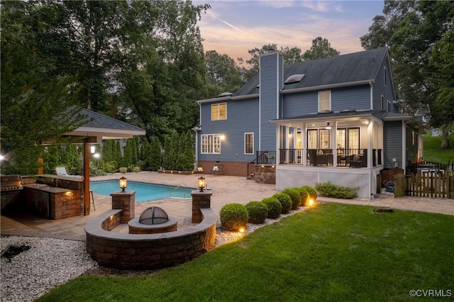 13908 Sunrise Bluff Rd, Midlothian, VA 23112 - back of house at dusk featuring an outdoor fire pit, a patio, a chimney, an outdoor kitchen, and a wooden deck