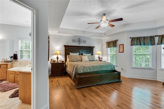 12300 Wynnstay Ln, Chesterfield, VA 23838 - bedroom featuring multiple windows, a tray ceiling, light wood-style floors, a textured ceiling, and baseboards