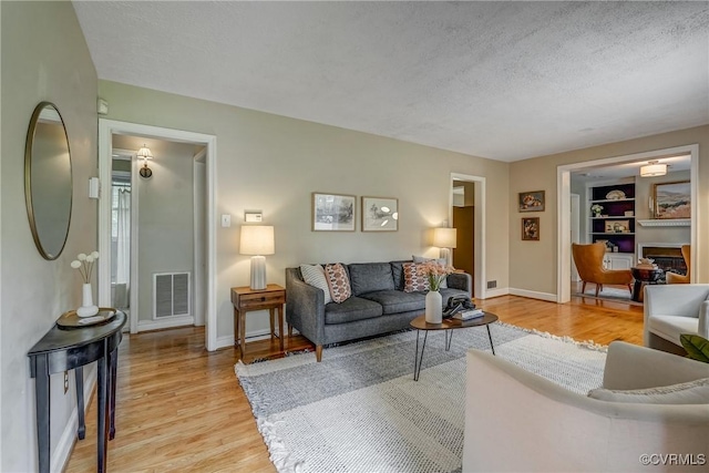 7400 Westfield Rd, Henrico, VA 23226 - living room featuring light wood-style flooring, a textured ceiling, baseboards, and built in shelves