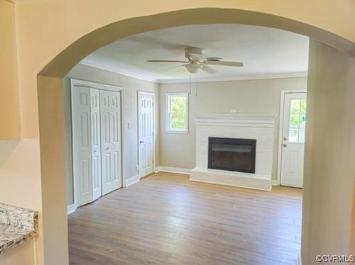 1217 Arlington St, Petersburg, VA 23803 - unfurnished living room featuring ceiling fan, crown molding, wood finished floors, a fireplace, and arched walkways