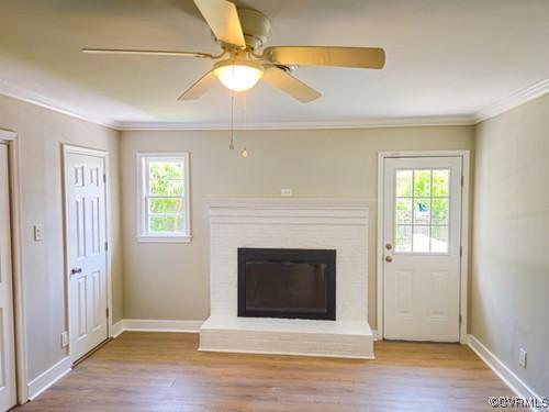 1217 Arlington St, Petersburg, VA 23803 - unfurnished living room with ornamental molding, wood finished floors, a brick fireplace, and ceiling fan