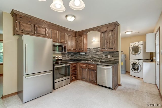 4509 Lockin Rd, Powhatan, VA 23139 - kitchen featuring appliances with stainless steel finishes, stacked washer / drying machine, a sink, dark countertops, and backsplash