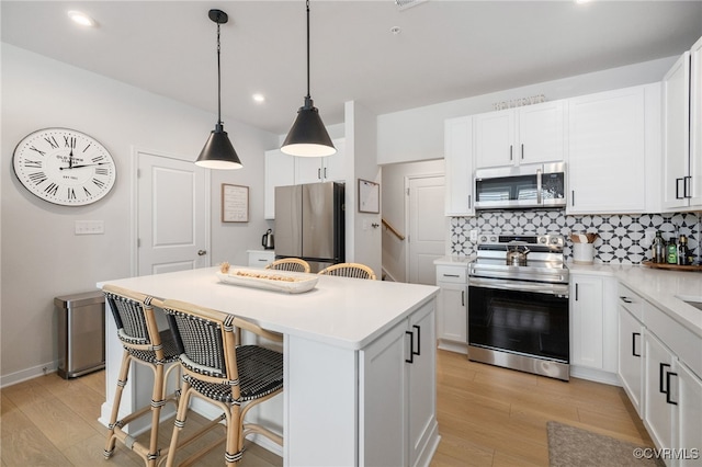 1900 Roseneath Rd Unit 8B, Richmond, VA 23230 - kitchen featuring stainless steel appliances, light wood-type flooring, a kitchen island, a kitchen bar, and tasteful backsplash