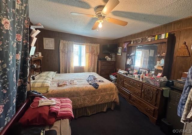 2095 Beef Rd, Greenville, VA 23847 - carpeted bedroom featuring a textured ceiling, wooden walls, and a ceiling fan