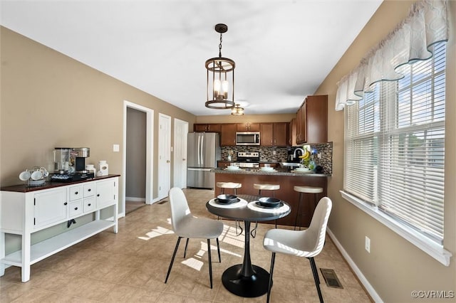7012 Autumn Point Dr, North Chesterfield, VA 23234 - kitchen with appliances with stainless steel finishes, dark countertops, backsplash, brown cabinets, and decorative light fixtures