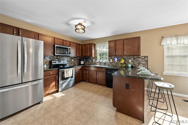 7012 Autumn Point Dr, North Chesterfield, VA 23234 - kitchen featuring appliances with stainless steel finishes, a peninsula, a breakfast bar area, decorative backsplash, and a sink