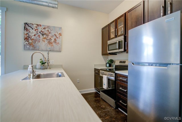 1020 Porter St Unit 103, Richmond, VA 23224 - kitchen featuring stainless steel appliances, a sink, light countertops, dark brown cabinets, and glass insert cabinets
