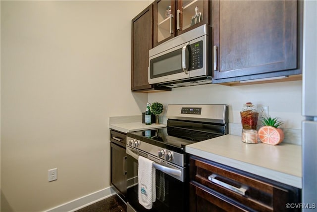 1020 Porter St Unit 103, Richmond, VA 23224 - kitchen with appliances with stainless steel finishes, dark brown cabinets, light countertops, baseboards, and glass insert cabinets