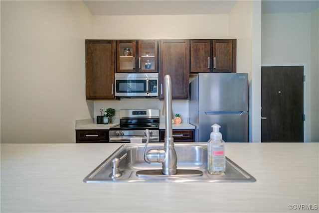 1020 Porter St Unit 103, Richmond, VA 23224 - kitchen featuring appliances with stainless steel finishes, light countertops, dark brown cabinets, and glass insert cabinets