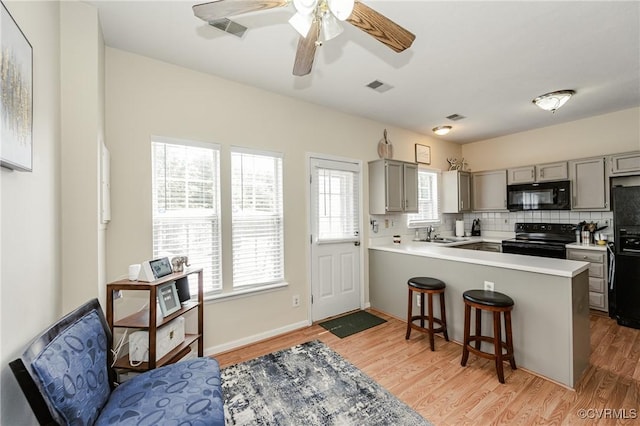 2906 Mary Beth Ln, Henrico, VA 23060 - kitchen featuring black appliances, gray cabinets, a sink, a breakfast bar, and light wood-type flooring