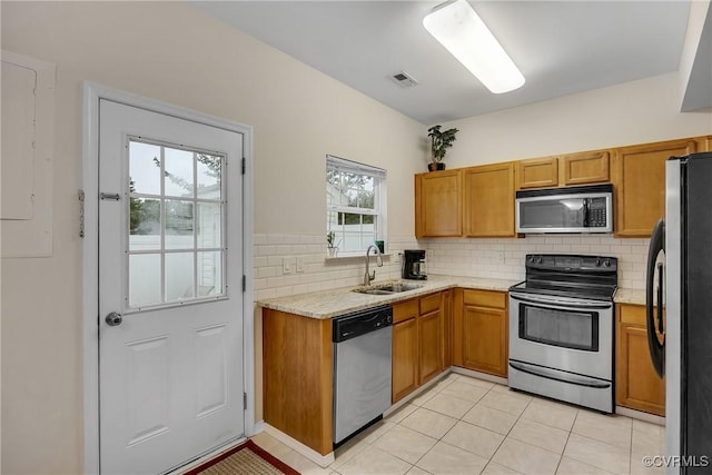 4613 Milfax Rd, Chesterfield, VA 23224 - kitchen with appliances with stainless steel finishes, tasteful backsplash, brown cabinets, light tile patterned flooring, and light stone counters