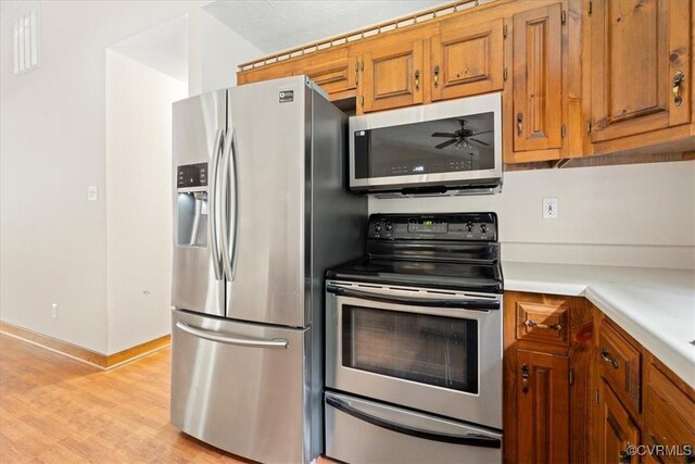 3786 Donavon Mill Ct, Powhatan, VA 23139 - kitchen with stainless steel appliances, brown cabinetry, light countertops, light wood-style floors, and ceiling fan