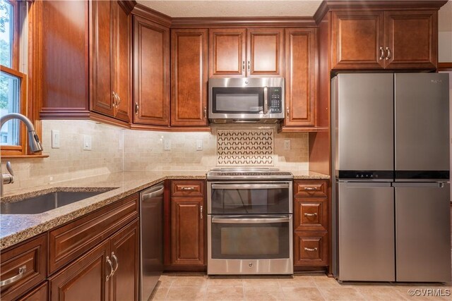 13100 Spring Trace Pl, Midlothian, VA 23112 - kitchen featuring stainless steel appliances, light stone countertops, decorative backsplash, and brown cabinetry