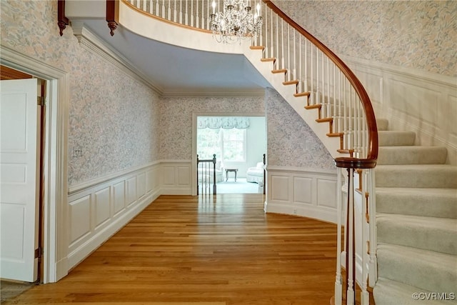 3320 Traylor Dr, Richmond, VA 23235 - stairs with wallpapered walls, wood finished floors, a decorative wall, a chandelier, and wainscoting