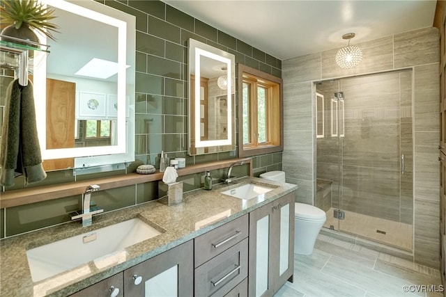 2940 Queenswood Rd, Midlothian, VA 23113 - full bathroom with tile walls, double vanity, toilet, a shower stall, and a skylight