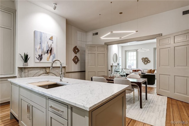 2311 E Broad St, Richmond, VA 23223 - kitchen featuring a sink, light wood finished floors, an island with sink, and light stone countertops