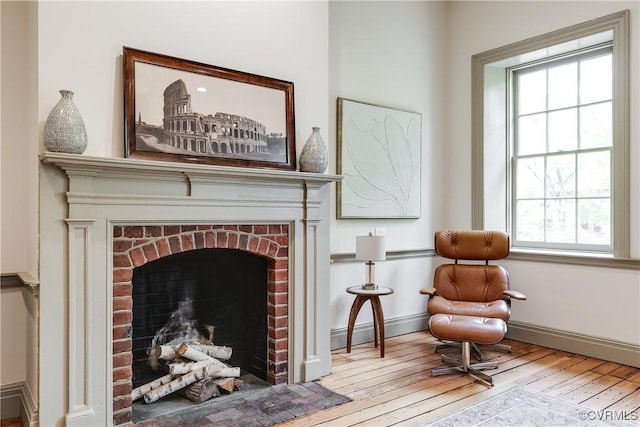 2311 E Broad St, Richmond, VA 23223 - living area with baseboard heating, wood-type flooring, plenty of natural light, and a brick fireplace