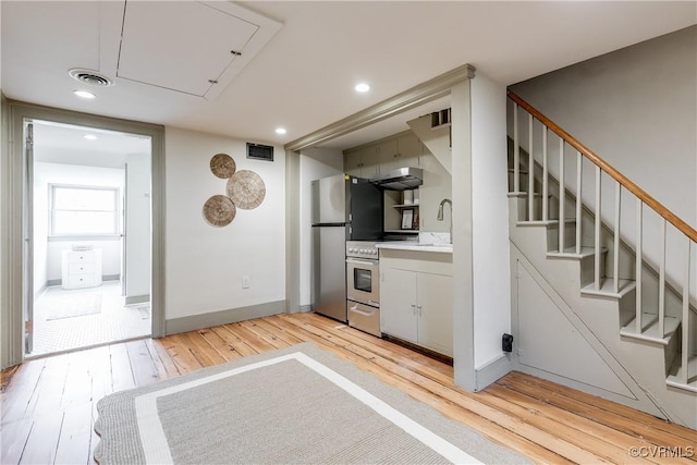 2311 E Broad St, Richmond, VA 23223 - kitchen featuring stainless steel appliances, light wood-style floors, light countertops, a sink, and baseboards