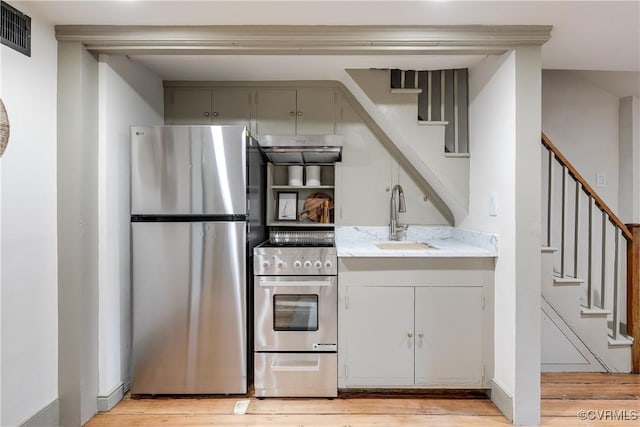 2311 E Broad St, Richmond, VA 23223 - kitchen with appliances with stainless steel finishes, light wood-style floors, a sink, gray cabinets, and light stone countertops