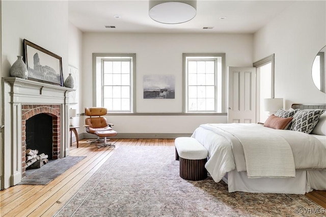 2311 E Broad St, Richmond, VA 23223 - bedroom featuring wood-type flooring, multiple windows, and a brick fireplace