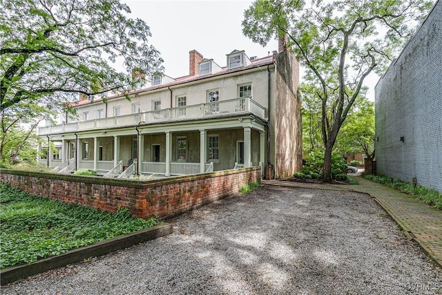 2311 E Broad St, Richmond, VA 23223 - back of house featuring a porch, a chimney, stucco siding, and a balcony
