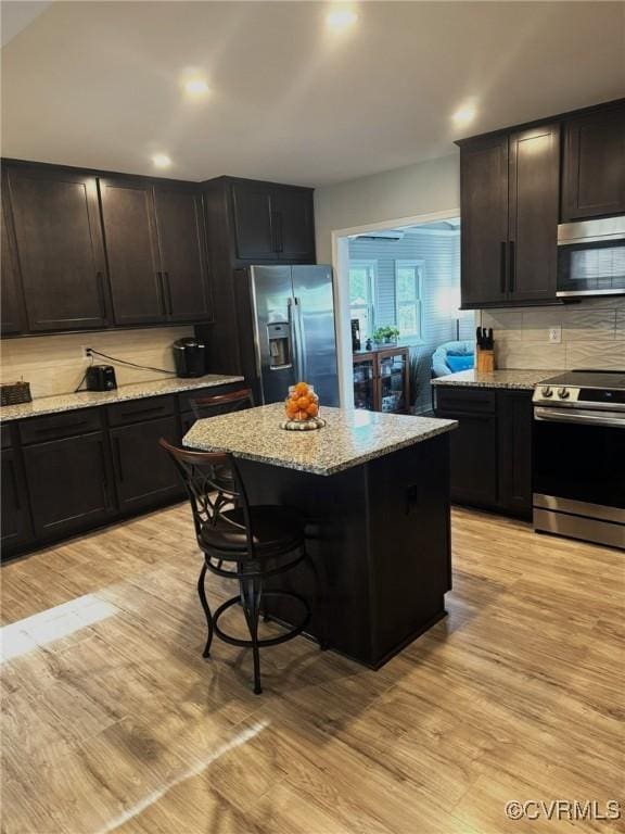 5630 Autumnleaf Dr, Chesterfield, VA 23234 - kitchen featuring appliances with stainless steel finishes, decorative backsplash, light stone counters, and a center island