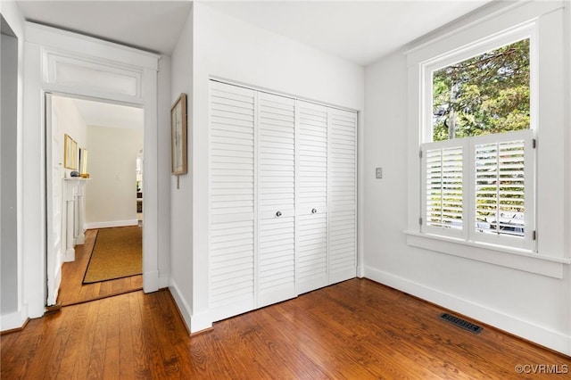 4500 Forest Hill Ave, Richmond, VA 23225 - unfurnished bedroom with wood finished floors, a closet, multiple windows, and baseboards